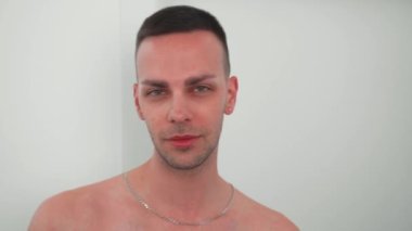 Mutlu, kendine güvenen beyaz bir gencin yakın plan görüntüsü aynada kendine bakıyor ve beyaz arka planda tek başına duruyor. Yüksek kalite 4k görüntü