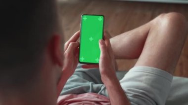 Green Mock-up Screen, Swiping, Scrolling Jestleri ile Akıllı Telefonu Dikey Kipte Kullanan Adam. Guy Cep Telefonu, İnternet Sosyal Ağ Tarayıcı Haberleri, Finans Haberleri. Görünüm Kamerası Noktası