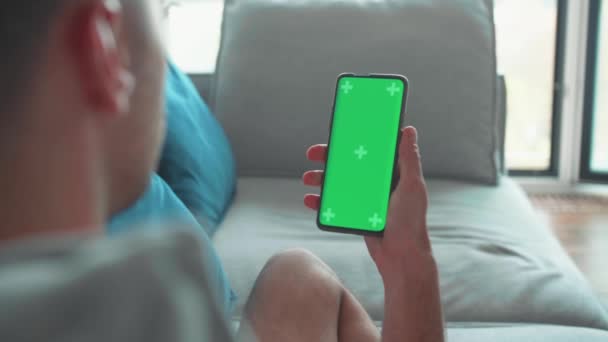 Młody Biały Mężczyzna Domu Leżący Kanapie Pomocą Smartfona Zielonym Ekranem — Wideo stockowe