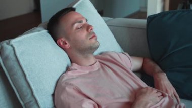 Sakin, Kafkasyalı genç bir adam kanepede dinleniyor gözleri kapalı uyuyor, mutlu, sağlıklı bir adam uyuyor. Yüksek kalite 4k görüntü
