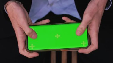 Akıllı telefonuyla video oyunu oynayan adamın en iyi görüntü görüntüsünü yakın çekim, kroma tuşlu yeşil ekran, hızlı bir şekilde ekrana vuruyor - bağlantı, teknoloji konsepti 4k video şablonu bankta. Yüksek