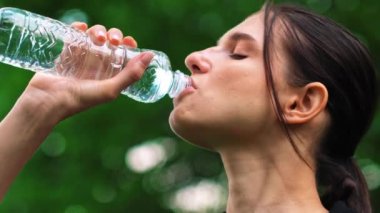 Spor yaptıktan sonra şişeden su içen kadın antrenmandan sonra açık hava esmer Latin kız temiz maden suyu içiyor. Yüksek kalite 4k görüntü