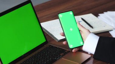 Akıllı telefon yeşil ekran ve dizüstü bilgisayar Chromakey kullanan kadını kapatın. Kadın eli cep telefonu tutarken yakın çekim. Krom anahtar ve yeşil ekran kavramı. Yüksek kalite 4k görüntü