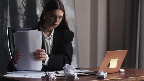 ストレスを受けたビジネス女性は ノートパソコンと粉砕された紙で机に座り 疲れたクランプ紙を感じ 集中力の問題 アイデアの欠如 作家ブロック 創造的な危機 期限の概念を投げます — ストック動画