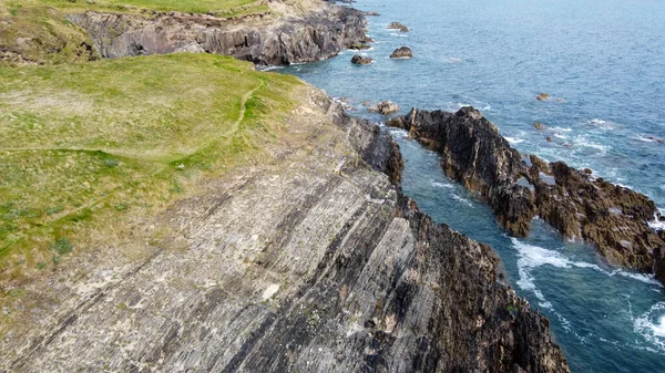 ケルト海の絵のように美しい岩の海岸 波の上に白い泡 サーフィン 石の丘の表面に厚い緑の草 ドローン写真 — ストック写真