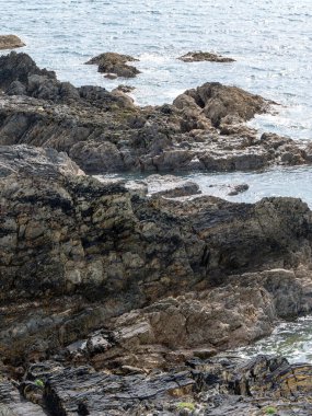 Sahilde açıkta duran kayalar. Güneşli havada deniz kenarında, suyun yanında kaya oluşumu.