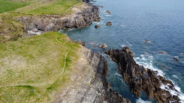 ケルト海の絵のように美しい岩の海岸 波の上に白い泡 サーフィン 石の丘の表面に厚い緑の草 — ストック写真