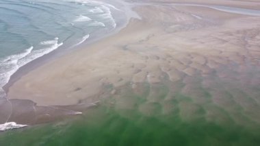 Kumlu bir sahil ve güzel gel-git dalgaları. Dalgalarda beyaz deniz köpüğü. Deniz manzarası, İHA videosu. Atlantik Okyanusu 'nun yüzeyindeki dalgalar, gelgit..