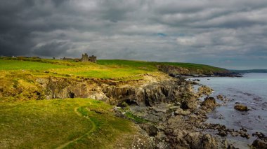 İrlanda 'nın kayalık kıyıları üzerinde bulutlu bir gökyüzü. Kuzey Avrupa 'nın güzel doğası. Sahildeki yeşil alanlar. Drone fotoğrafı.
