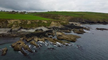 Atlantik kıyısındaki yemyeşil tepeler, Kuzey Avrupa 'nın doğası. Rocky sahil şeridi. Bulutlu bir günde deniz manzarası. Bulutlu hava, kasvetli gökyüzü. Hava fotoğrafı.