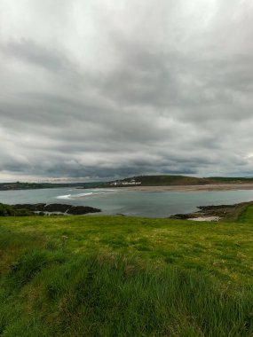 Deniz koyunun yakınındaki tepede sık yeşil çimenler. Clonakilty Körfezi üzerinde bulutlu bir gökyüzü, deniz manzarası. Yukarıdan görüntüle.