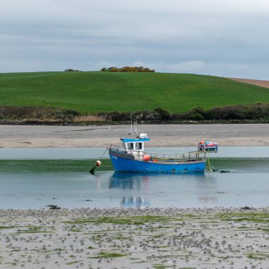 Sığ sularda bir tekne. Gökyüzünün altındaki tepeler.