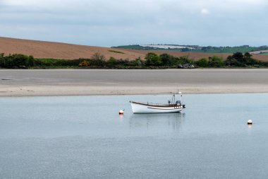 Sığ sularda bir motorlu tekne. Sakin su yüzeyi. Körfezin kıyısındaki resimli tepeler. Atlantik Okyanusunun kumlu kıyısı.