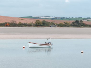 Bir motorlu tekne. Sakin su. Sahildeki resimli tepeler. Atlantik Okyanusunun kumlu kıyısı.