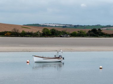Bir motorlu tekne. Sakin sular, sahildeki tepeler. Atlantik Okyanusunun kumlu kıyısı.
