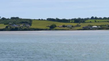 İrlanda 'da Atlantik Okyanusu kıyısındaki evler, kıyı manzarası. Açık bir gökyüzünün altında güneşli bir günde İrlanda kıyısı. Peyzaj.