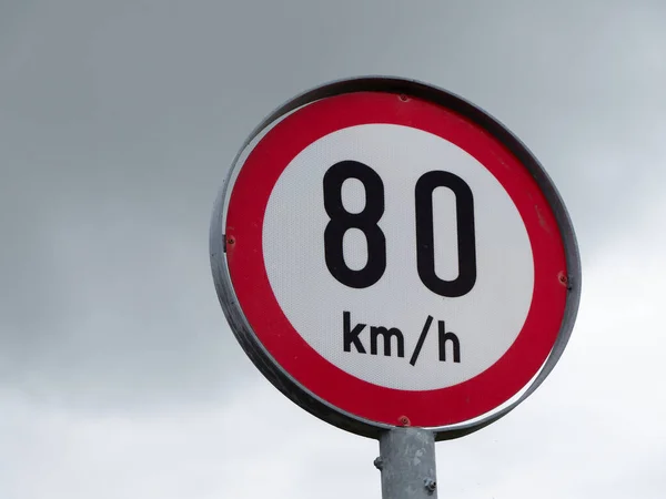 A road sign limiting the speed of 80 km per hour. A road sign against a sky.