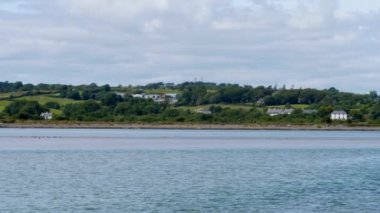 İrlanda kıyılarındaki evler, kıyı manzarası. Açık bir gökyüzünün altında güneşli bir günde İrlanda kıyısı. Peyzaj.