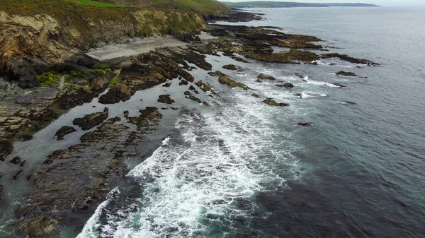 Tidal waves of the Atlantic Ocean. Rocks on the southern coast of the island of Ireland. White sea foam on the waves. Beautiful seaside landscape. Aerial photo.