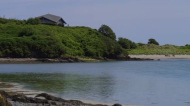 İrlanda 'da deniz kıyısında yeşil bir tepede ev, manzara.