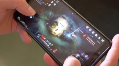 County Cork, İrlanda, 7 Ağustos 2022. Bir adam elinde akıllı bir telefon tutuyor ve MMORPG Black Desert Online oynuyor, yakın plan, resimli yazı. Cep telefonu ekranındaki video oyunu. Mobil bilgisayar oyunları.