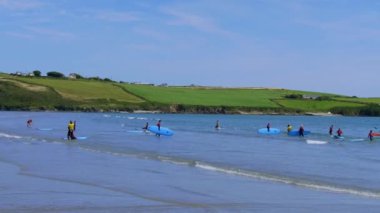 County Cork, İrlanda, 6 Ağustos 2022. İrlanda 'da deniz kıyısında yüzme tahtaları olan genç sörfçüler. Yaz aylarında su sporları severler.