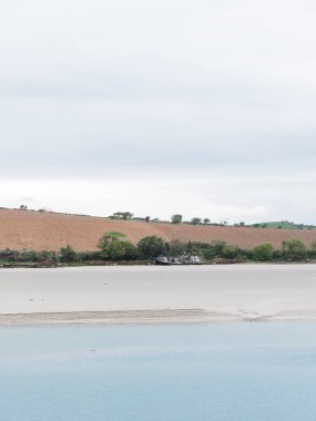 Kumsal kıyısı. Sakin su. Kıyıdaki gemi. Tarlaya sürülmüş. Minimalist manzara.