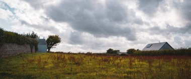 İrlanda 'daki köy evlerinin çatıları üzerinde dramatik bulutlu gökyüzü. Peyzaj.