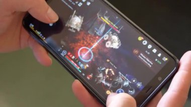 County Cork, İrlanda, 7 Ağustos 2022. Bir adam elinde akıllı telefon tutuyor ve MMORPG Black Desert Online oynuyor, resimli yazı. Oyuncuların elindeki telefon. Otomatik savaşları olan Kore video oyunu