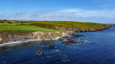 Güneşli bir bahar gününde Atlantik Okyanusu 'ndaki yeşil tepeler. Deniz kıyısında mavi gökyüzü. İrlanda kıyısı, West Cork. Drone fotoğrafı.