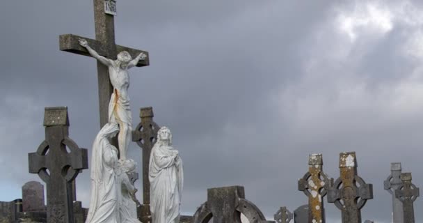 アイルランドのカトリック墓地でイエス キリストの大規模な石の十字架刑 ケルト人の十字架の形で墓石 キリスト教の墓地 墓の上に曇った空 — ストック動画