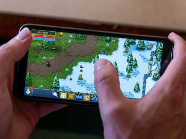 County Cork, İrlanda, 31 Temmuz 2022. Telefon beyaz bir adamın elinde. Bir akıllı telefon kullanıcısı bir video oyunu oynuyor. Warspear Online, resimli editör.