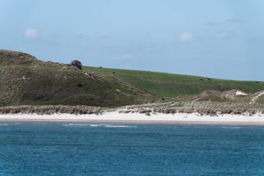 Mavi gökyüzünün altında bir deniz. Atlantik Okyanusu 'ndaki kumsal. Güneşli bir bahar gününde deniz kenarında İrlanda manzarası. Hilly Sahili.