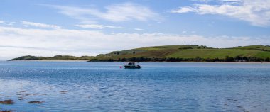 County Cork, Ireland, August 21, 2022. One small fishing boat on a calm water surface near the hilly Irish coast on a sunny summer day. boat on water