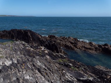 Picturesque coastal cliffs in blue sea water. Seaside landscape. Blue sea beside rock