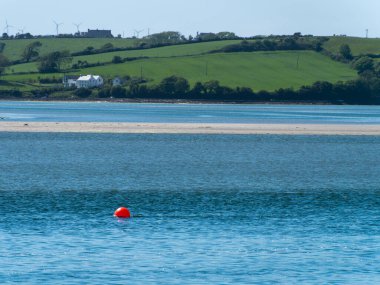 An orange sea buoy on the surface of the water on a sunny spring day. Seaside landscape.