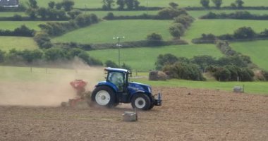 County Cork, Ireland, August 20, 2022. One tractor processes and sows a plowed field in summer. Agricultural work in the field.