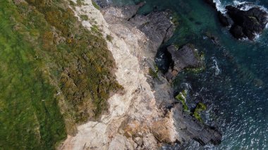 Dense green vegetation on the rocky coast of the Atlantic Ocean. Beautiful seaside landscape. Aerial photo.