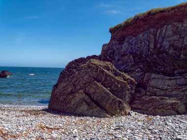 A beach on the Irish coast of the Atlantic Ocean on a sunny day. Picturesque rocky coast. Seascape, rock formation on sea shore.