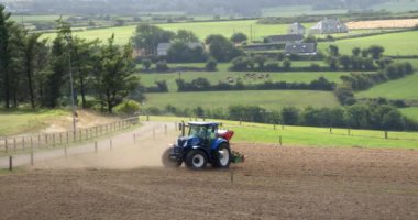 County Cork, Ireland, August 20, 2022. One blue tractor processes and sows a plowed field, summer. Agricultural work in the field.