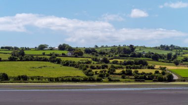 White clouds in the sky, countryside. Green hills on a summer. Irish countryside, County Cork. Green field under white clouds and blue sky