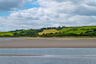 White cumulus clouds in the sky over the hilly Irish countryside. Green hills on a nice summer day. Irish countryside.