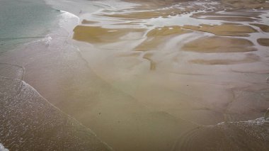 Sandy seashore, top view. Minimalistic seascape, a copy space. Wet sand. Natural background, texture. Peaceful beach background, sand and sea water. Ocean coastline of nice sand and calm waves.