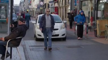 Cork, İrlanda, 30 Eylül 2022. Cork 'un merkezindeki bir şehir caddesi boyunca sakinlerin hareketi. Bir Avrupa şehrinin vatandaşları bir sabah caddede yürürler. video.