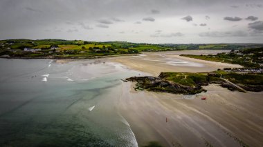 Grey sky, Inchydoney beach and Cape Virgin Mary on a summer day. The famous Irish tourist location. Picturesque Irish coast, top view.