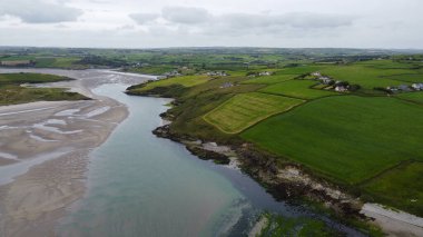 Green fields on the hills. The countryside of Ireland on a cloudy day. The coast of Clonakilty Bay at low tide. Green grass field under cloudy sky