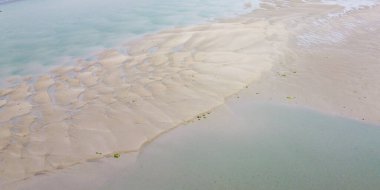Wet beach at low tide, top view. Minimalistic landscape, sand near body of water.
