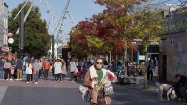 Cork, Ireland, September 30, 2022. A young white girl with flowers walks down the street of a European city. Passers-by on the street on a autumn morning. Townspeople in an Irish town.