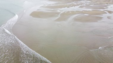 Sandy shore. Minimalistic seascape, a copy space. Wet sand. Natural background, texture. Peaceful beach background, sand and sea water. Ocean coastline of nice sand and waves.