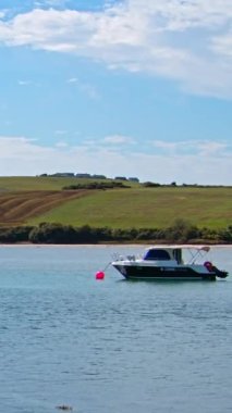 County Cork, Ireland, August 21, 2022. One small motorboat is anchored in Clonakilty Bay on a sunny day. Boat on the surface of the water off the Irish coast, seaside landscape. Vertical video.